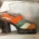 A closed toe platform sandal. The top is orange and green, and clearly mouldy.