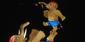 An illustration of two elephants performing a trick wearing swimming trunks and hat