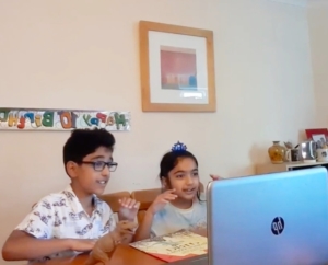 2 children are sitting in front of a laptop