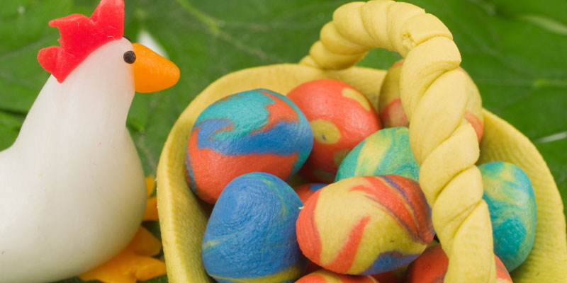 Clay Easter decorations including brightly coloured eggs in a basket and a sculpted chicken
