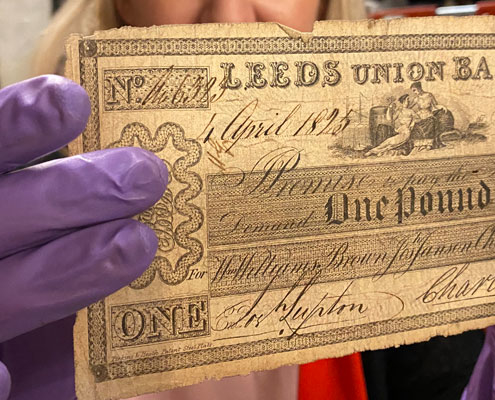 A curator holding a Leeds £5 note