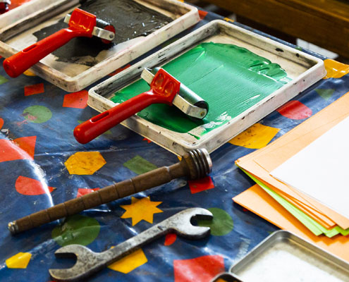 Print and craft materials are laid out on a table with a blue patterned plastic sheet