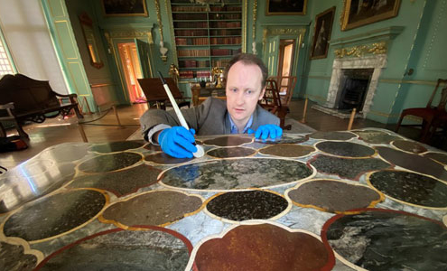 A man uses a brush on a fine marble table in Temple Newsam House
