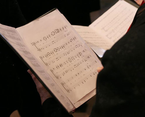 A choir book is being held up by a singer dressed in black