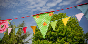 Patterned and brightly coloured bunting hangs against a bright blue sky
