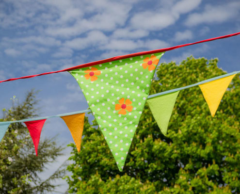 Patterned and brightly coloured bunting hangs against a bright blue sky