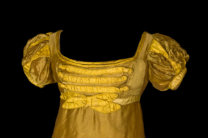 Detail of the top of a yellow silk ballgown with puffed short sleeves and a scooped neckline