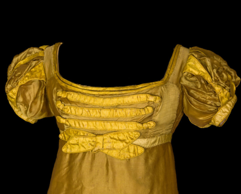 Detail of the top of a yellow silk ballgown with puffed short sleeves and a scooped neckline