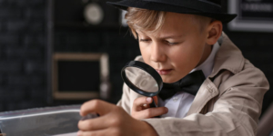 Young boy pretending to be a detective with a magnifying glass