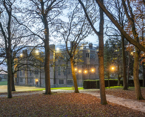 Temple Newsam at dusk with festoon lighting throughout the autumnal tree lined path to the house