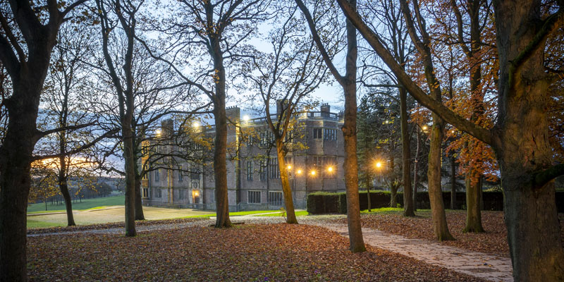 Temple Newsam at dusk with festoon lighting throughout the autumnal tree lined path to the house