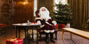 Father Christmas sat at a table in front of a Christmas tree in Temple Newsam House