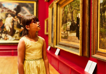 Young girl looking at paintings