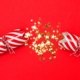 A red and white striped Christmas cracker broken in half with sparkly stars inside, on a red background
