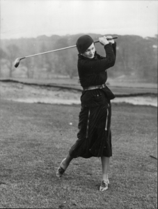 Black and white photograph of a woman playing golf.