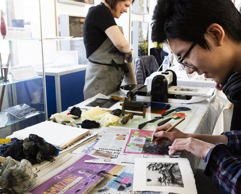 A man is taking part in print making activities held within a museum workshop setting