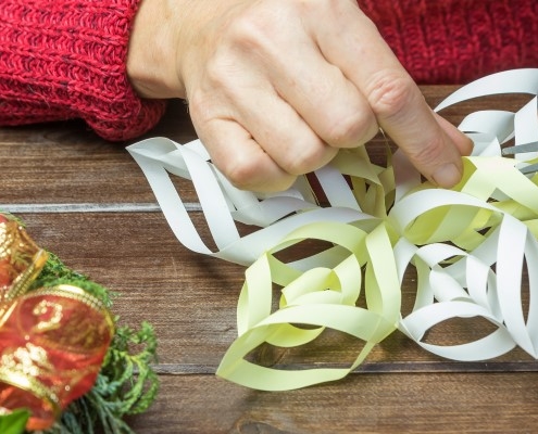 A person cutting paper star on wooden desk with a part of advent wreath