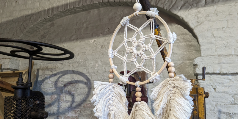 A dreamcatcher made from a wooden hoop, knotted string, and beads
