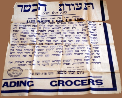 A white poster with blue printed Hebrew text advertising a grocers in Leeds