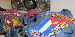 Two denim jackets which have been personalised with graffiti and images in bright colours, and a boom box in the background