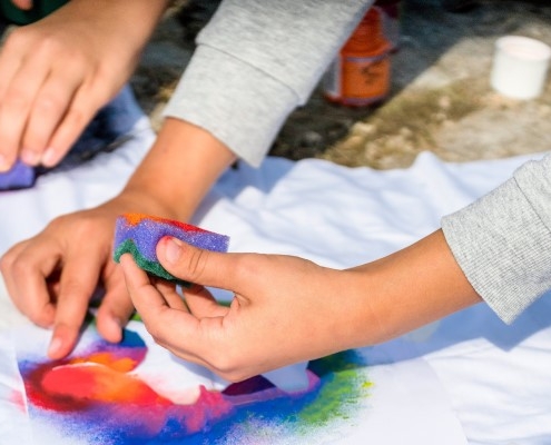 People printing with coloured paints on white t shirts