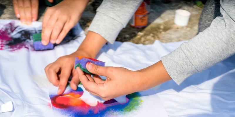 People printing with coloured paints on white t shirts
