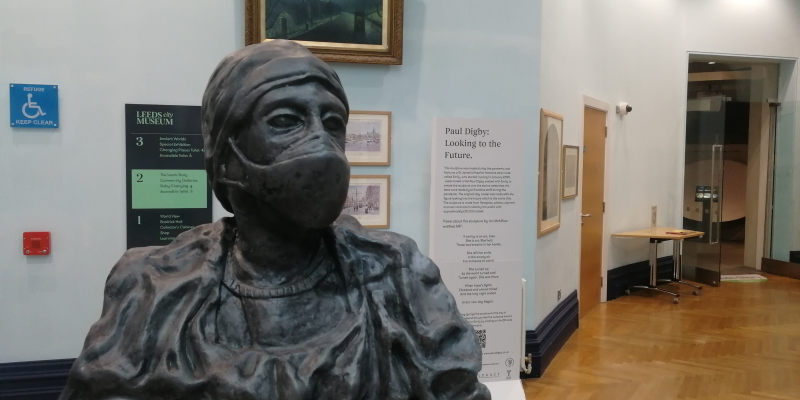 Statue of a person wearing scrubs and a face mask