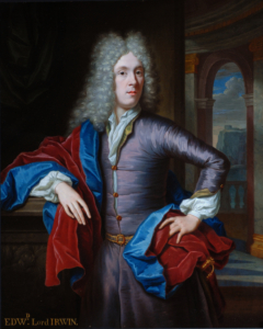 painting of a well dressed man wearing a grey silk coat and a grey curly wig, holding blue and red draped fabrics