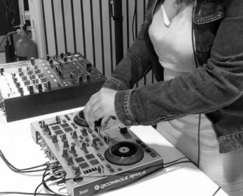 Black and white photograph of youth collective member Cara Mia DJing