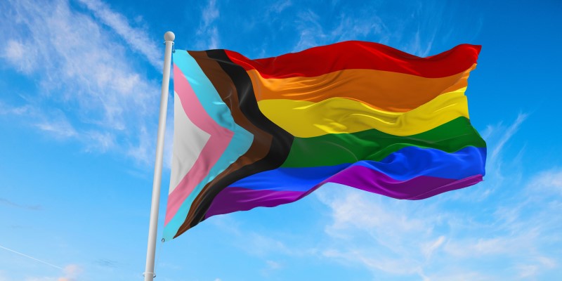 Pride flag blowing in the wind with blue sky behind