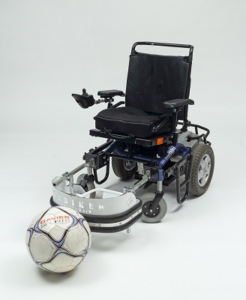 a power wheelchair with a football on the floor in front of it