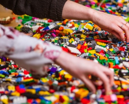 Two people's hands and a big pile of lego