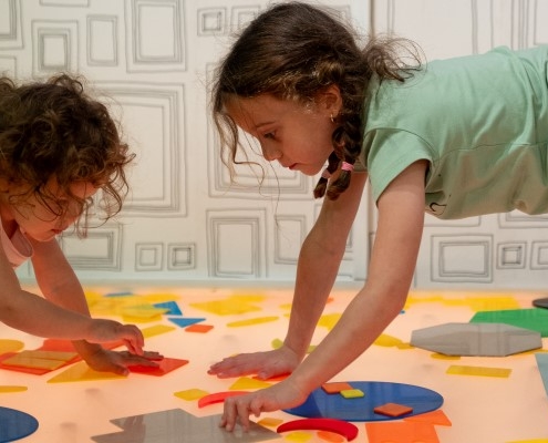 two children moving coloured shapes around on a light up surface