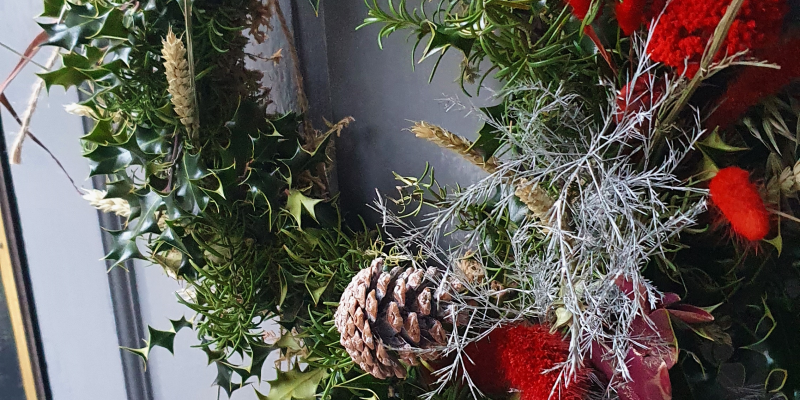 Christmas wreath on door with leaves and pine cones