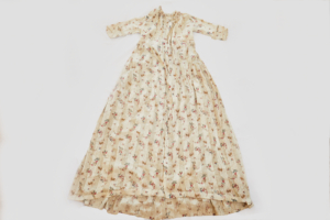 A long, cream coloured dress with elbow length sleeves and a printed floral pattern