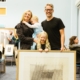 Two parents and two children smiling and holding a framed picture from the picture library