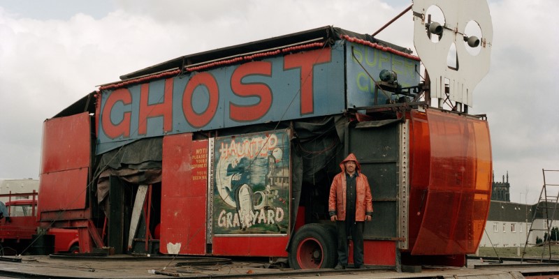photo of a train with the word 'ghost' painted on the side in large lettering, a man standing next to it