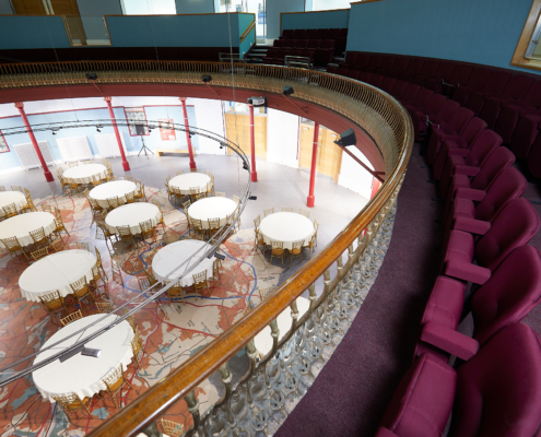 A balcony in a circular room with 9 round tables below