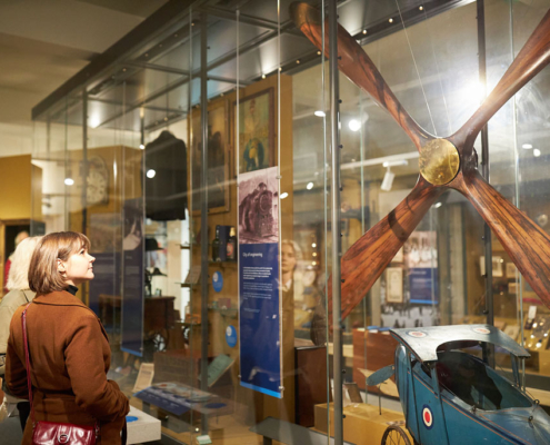 Two people looking at objects in a case within the Leeds Story gallery at Leeds City Museum.