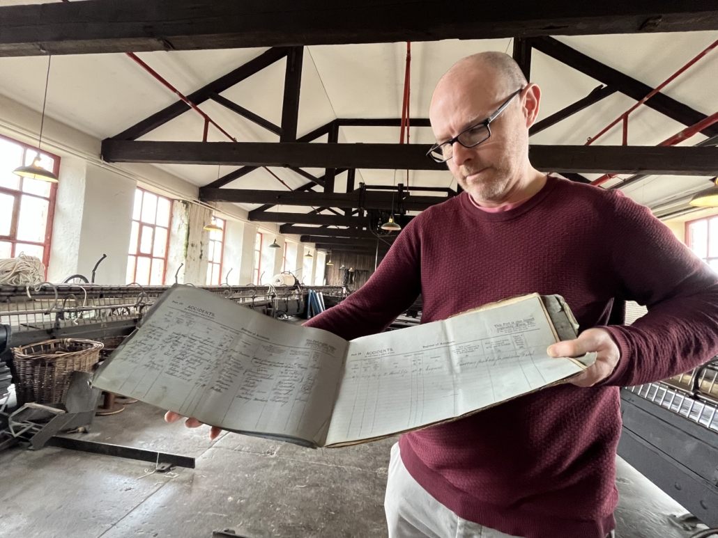 A curator holds an old accident book in a mill
