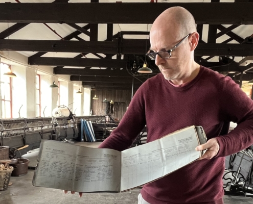 A curator holds an old accident book in a mill