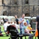 people sitting at picnic tables in kirkstall abbey with market stalls in the background