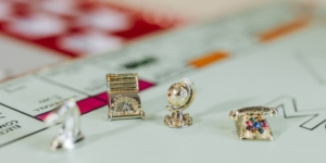 monopoly board with tiny golden playing pieces in the shape of a horse, glove and telephone