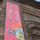 A section of the exterior of Leeds City Museum building with a large vertical banner to advertise the exhibition - Living with Death.