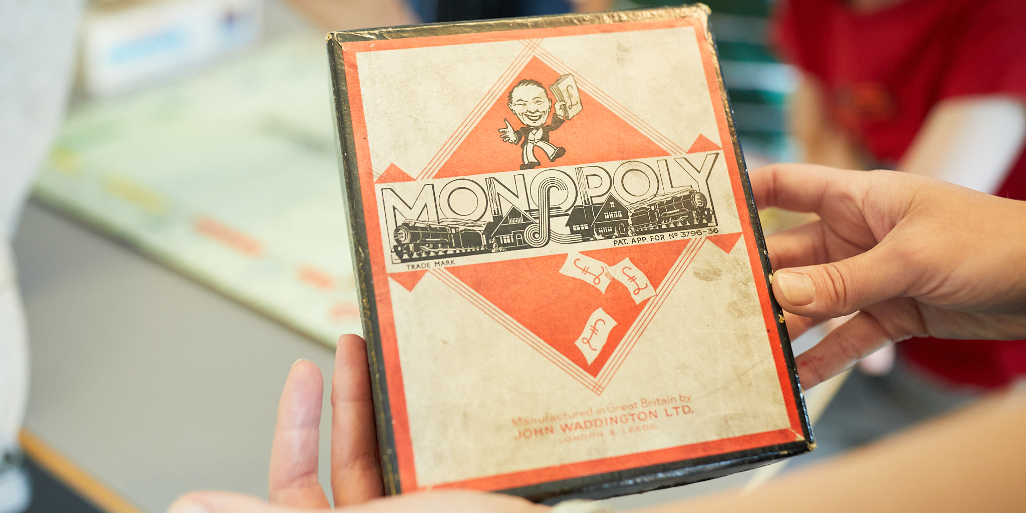 Two hands holding an old monopoly board game box