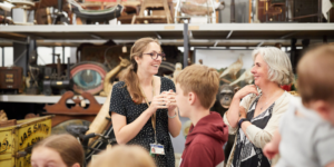 A tour guide in Leeds Discovery Centre with objects and people surrounding them